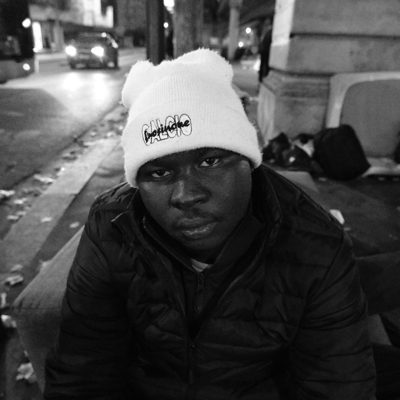 Young man in a white beanie and puffer jacket at night